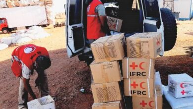 Sudanese Red Crescent Society volunteers offload relief items and set up relief tents to support families on the move who are fleeing fighting in Sudan in April 2023.