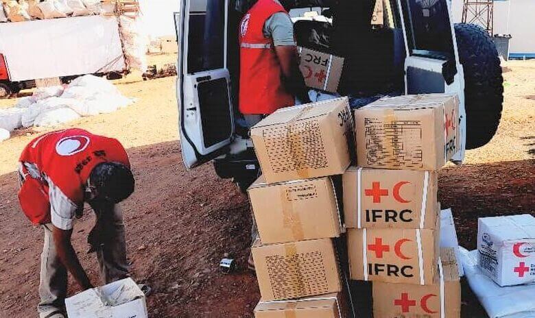 Sudanese Red Crescent Society volunteers offload relief items and set up relief tents to support families on the move who are fleeing fighting in Sudan in April 2023.